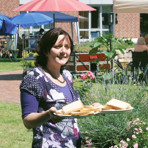 Eine Frau trägt ein Kuchentablett in einem Garten